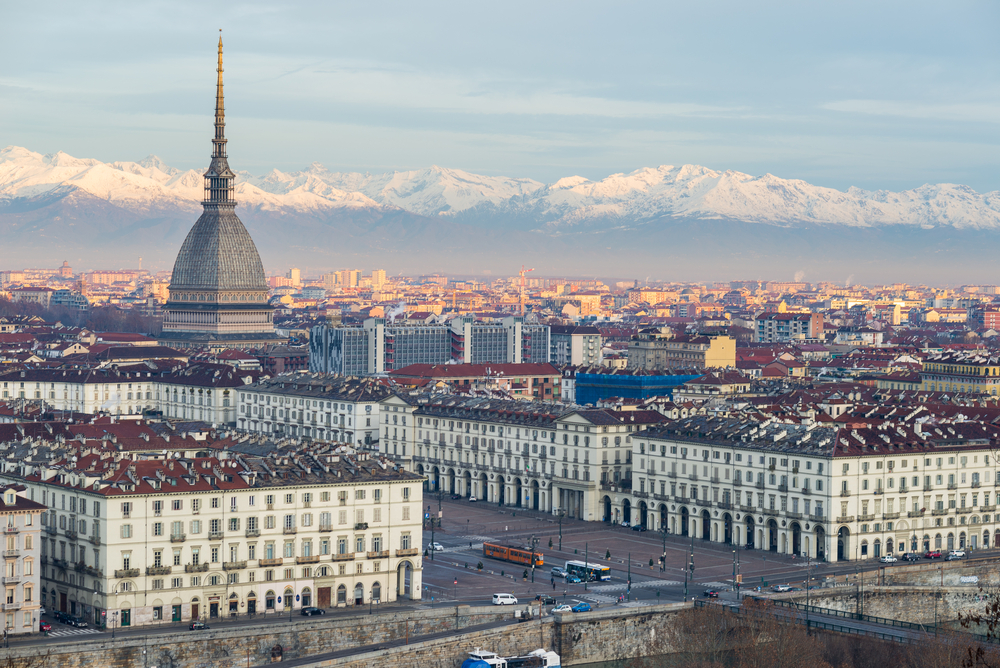 Torino (Turin, Italy): cityscape at sunrise with details of the Mole Antonelliana towering over the city. Scenic colorful light on the snowcapped Alps in the background.