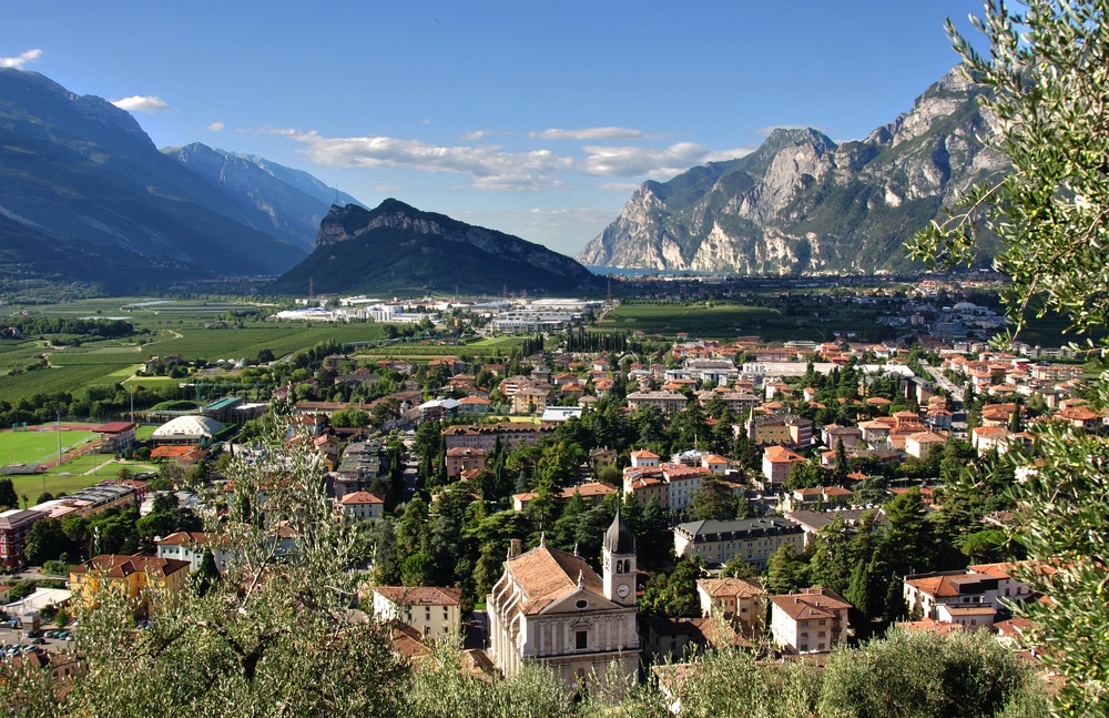 birds-eye view of town rooftops surrounded by greenery and mountains in the background - Arco, Lake Garda
