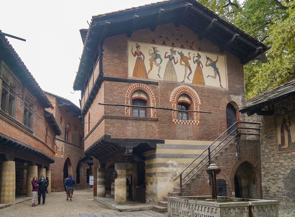 Borgo Medievale in Turin - focus of a brick building with a frescoe on the side and a fountain in a village square