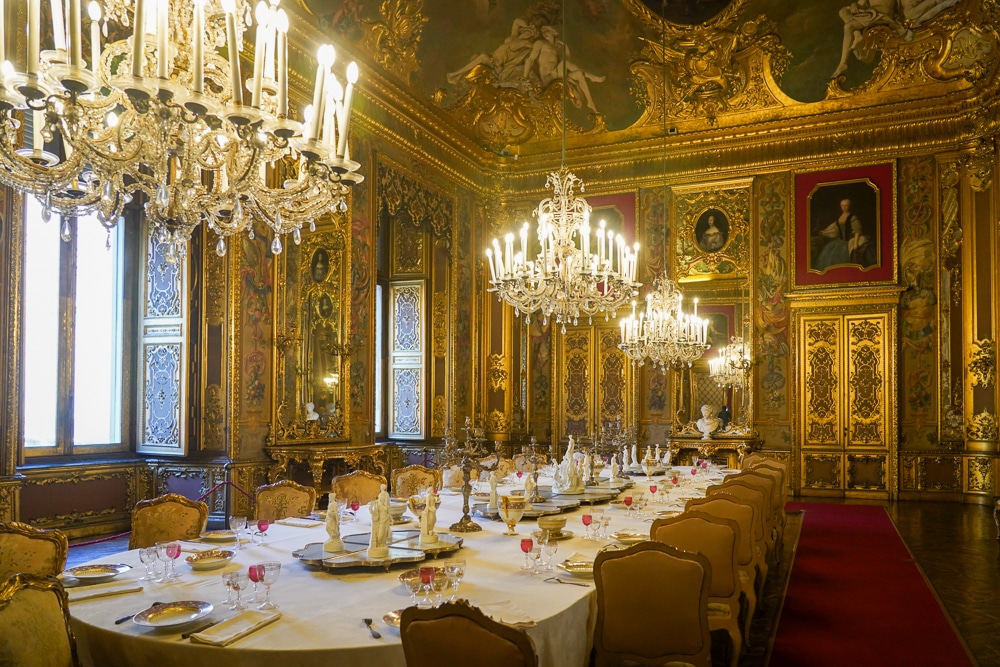 Dining room in the Royal Palace in Turin Italy with gold moldings, ornate decorations and furnishings, and chandeliers