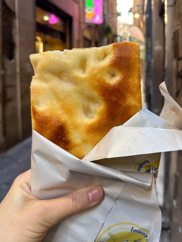 a hand holding a piece of focaccia in Genoa Italy