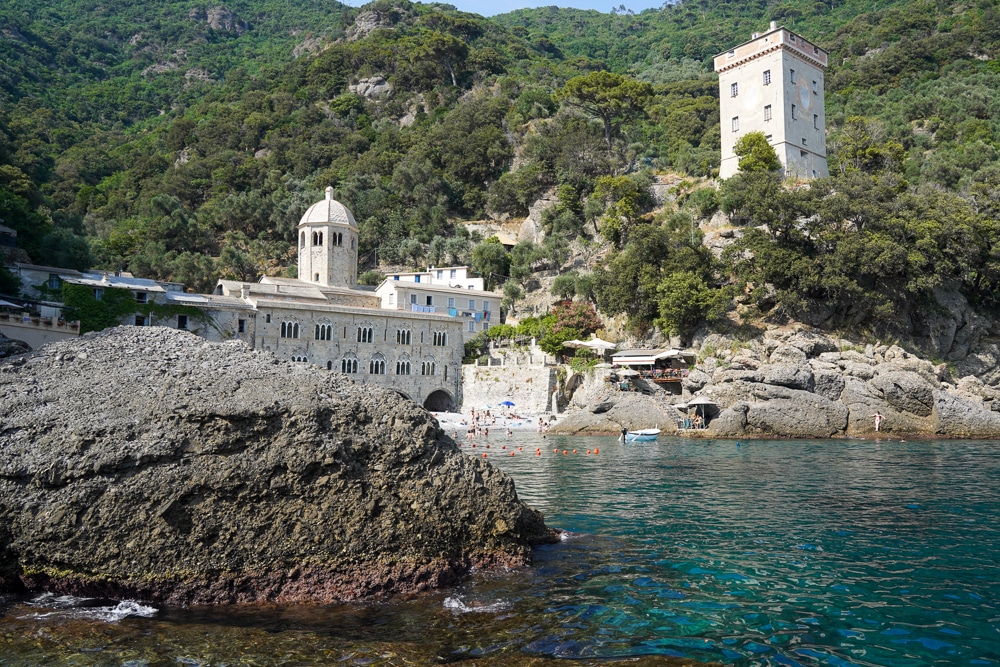 Arriving by boat to San Fruttuoso Liguria. Turquoise water in the foreground and the abbey and tower in the background