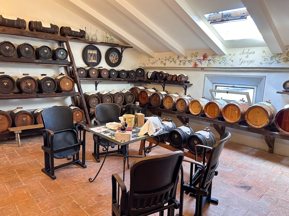 balsamic vinegar aging room with wooden barrels on shelves and a table for tastings at Acetaia di Giorgio in Modena Emilia Romagna Italy