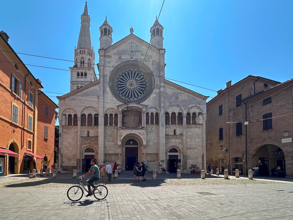 church in modena italy on a sunny day with a cyclist passing by