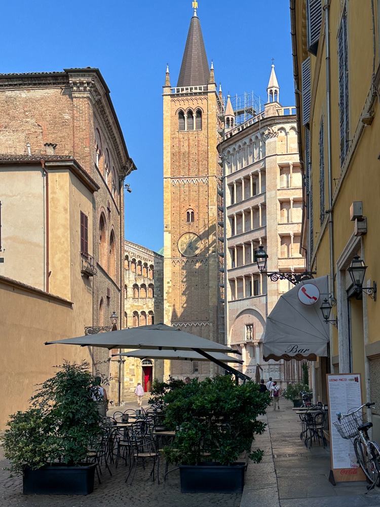Parma Italy side street view of a cafe and the cathedral and baptistery in the background