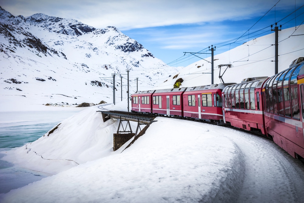red train in winter heading into the snowy Alps