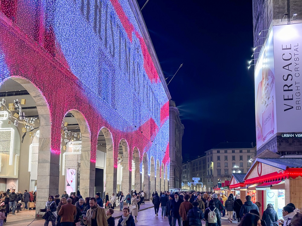 Christmas lights in Milan covering a building facade with people walking