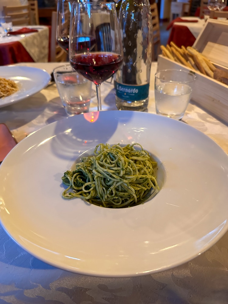 Pasta with pesto and a class of wine on a restaurant table in Italy