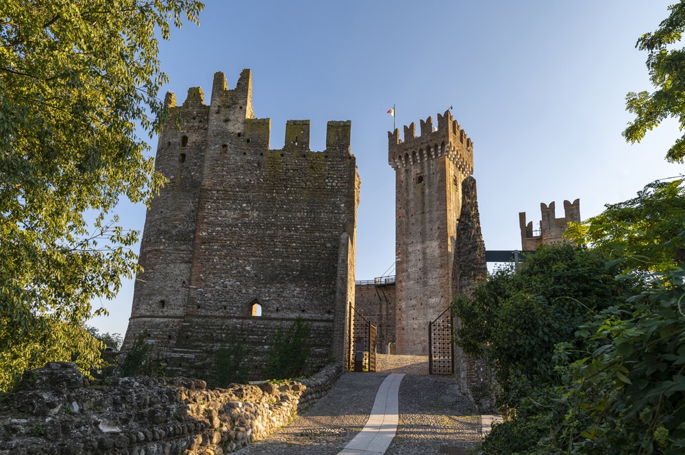 Entrance to the medieval Scaligero castle of Valeggio sul Mincio, detail of the brick remains, the tower and the crenellated walls, in a summer day with blue sky. Italy