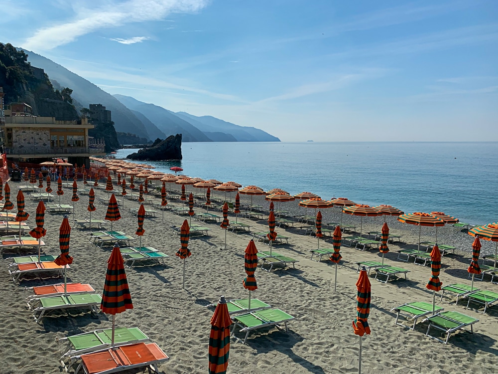 beach with lounge chairs and closed umbrellas in monterosso in cinque terre italy