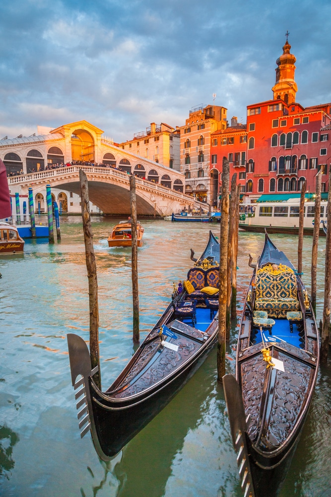 closeup of gondolas in venice with a bridge and colorful buildings in the background