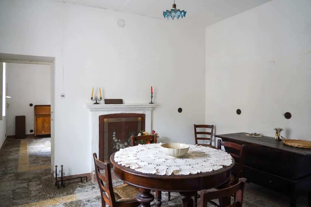old Italy house room with white plaster walls and a round antique table at the center