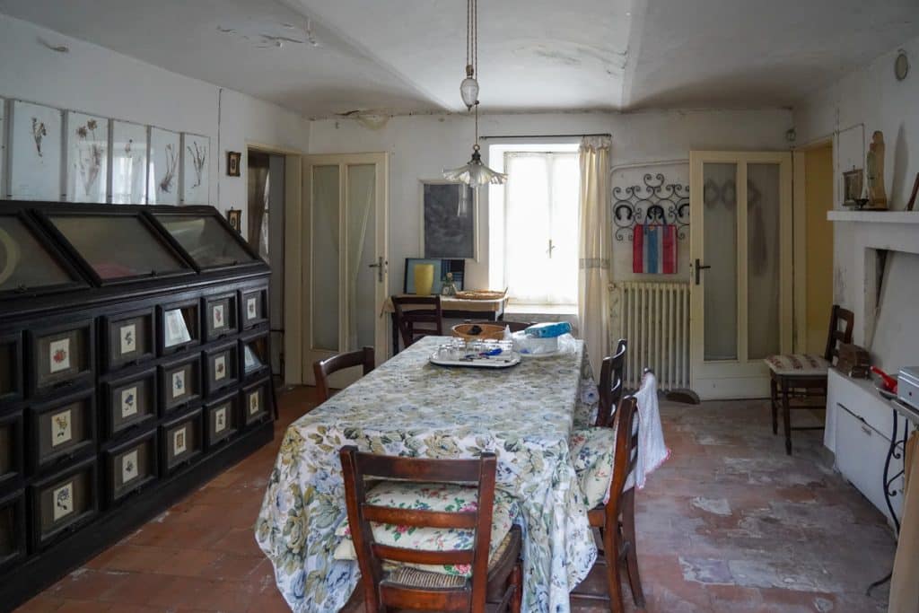 inside of an old house in italy with a table at the center and antique furniture on the left