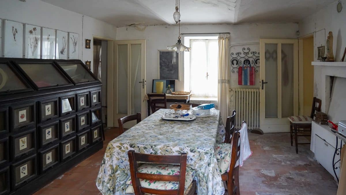 inside of an old house in italy with a table at the center and antique furniture on the left