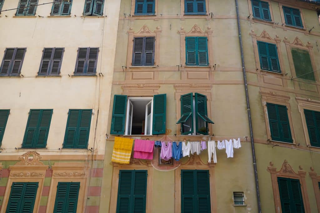 peach and orange colored buildings with green shutters and laundry hanging in Camogli Italy