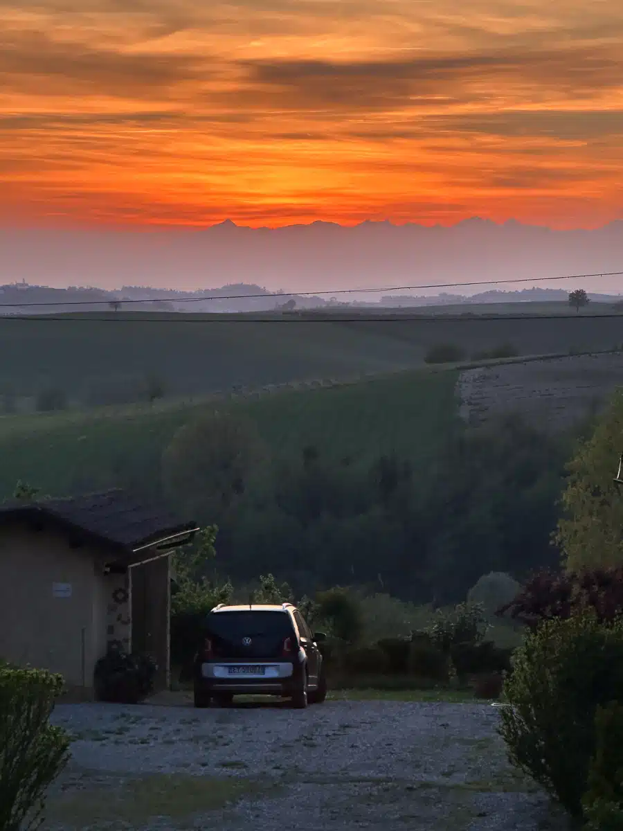 sunset in Monferrato with the alps on the horizon and a car parked in the foreground