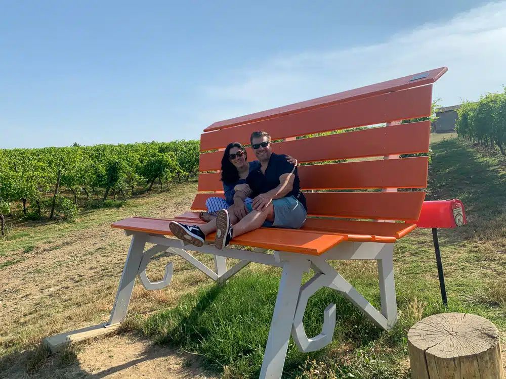 man and woman sitting on a big orange bench in Monferrato Italy